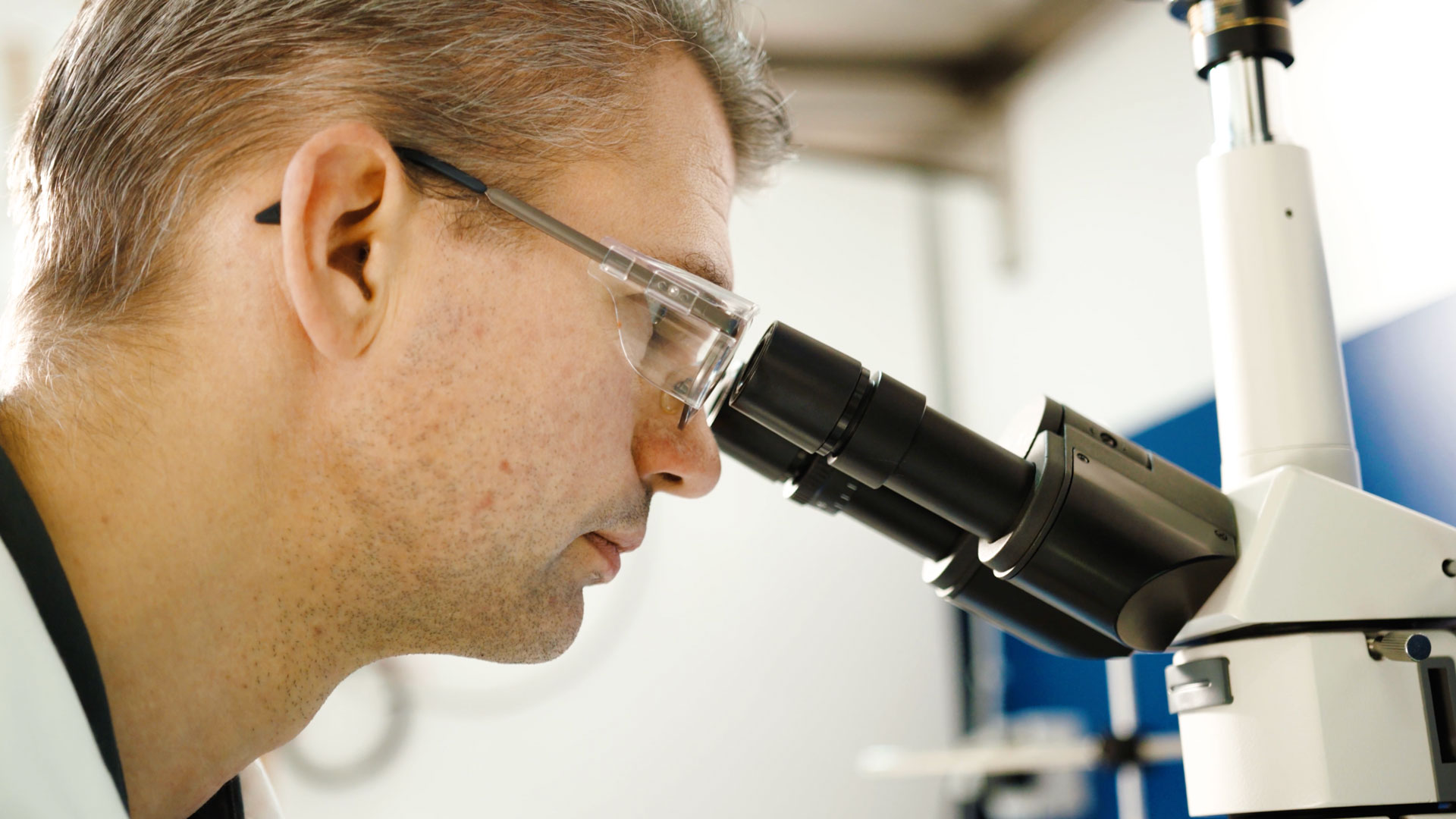 man tittar in i mikroskop